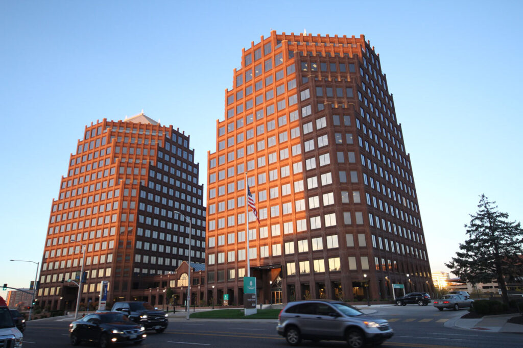 Two large buildings with a street and passing cars in the foreground