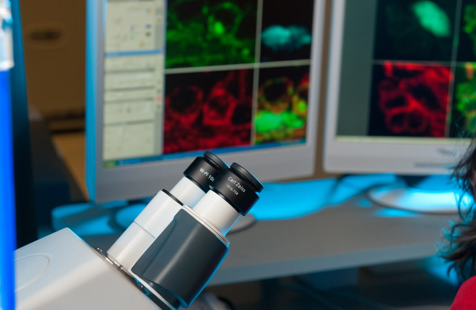 A microscope with colorful scientific images on a computer screen