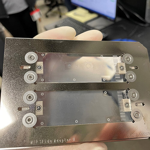 Gloved hand holding a slide adapter.