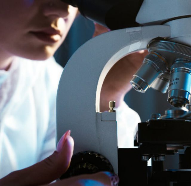 A closeup of a scientist looking into a microscope