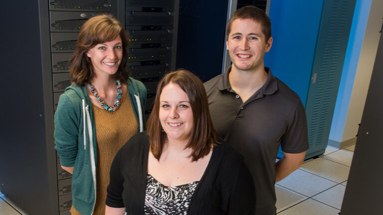 Three people smiling and looking up at camera