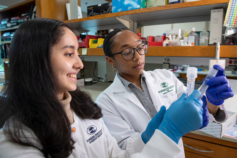 Two female scientists looking at liquid in plastic tubes with caps