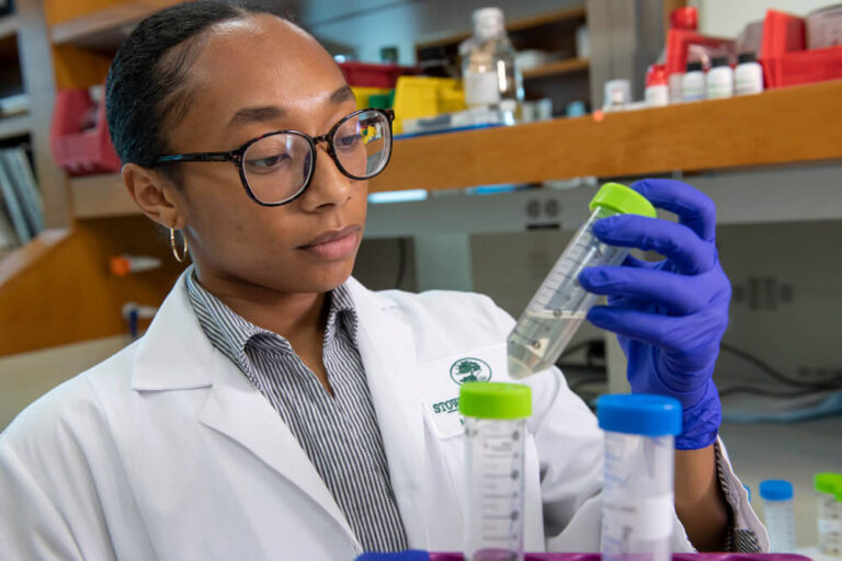 Scientist looking at test tube with gloves on